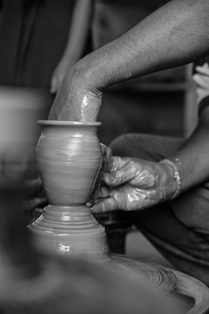 Close-up of hands sculpting clay on a potter's wheel, showcasing craftsmanship and artistry.