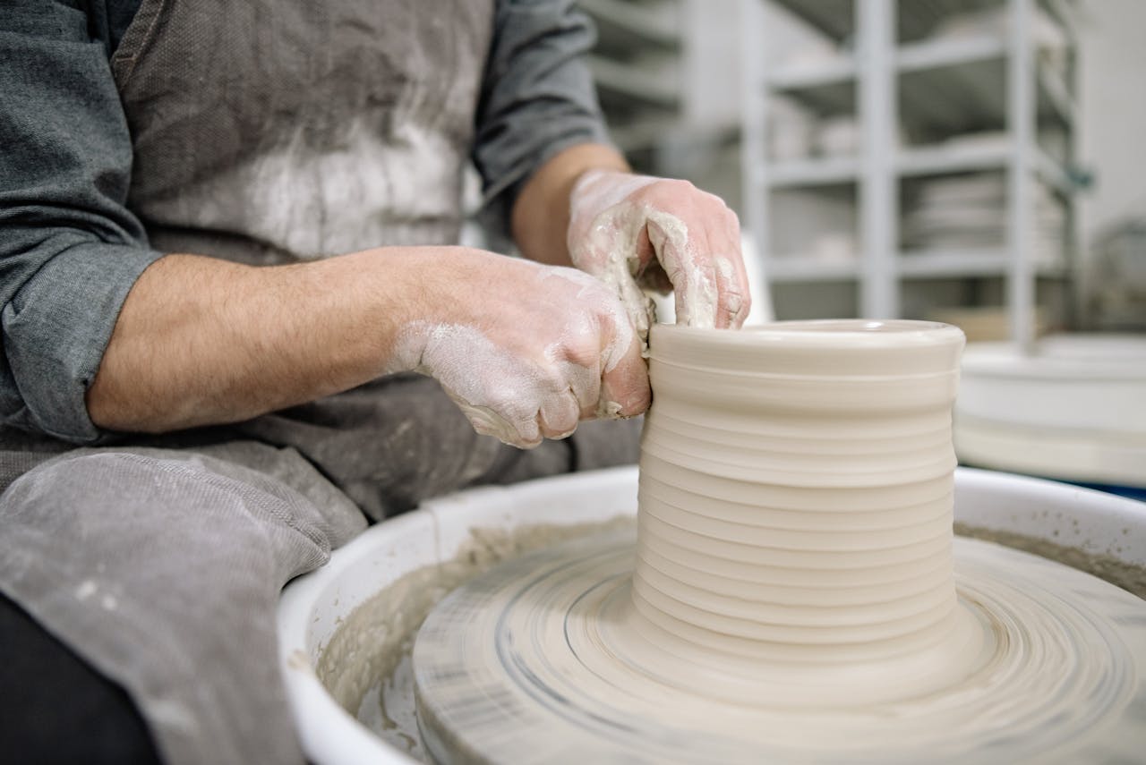 digital Potter shaping clay on a pottery wheel, showcasing artisan skill indoors.